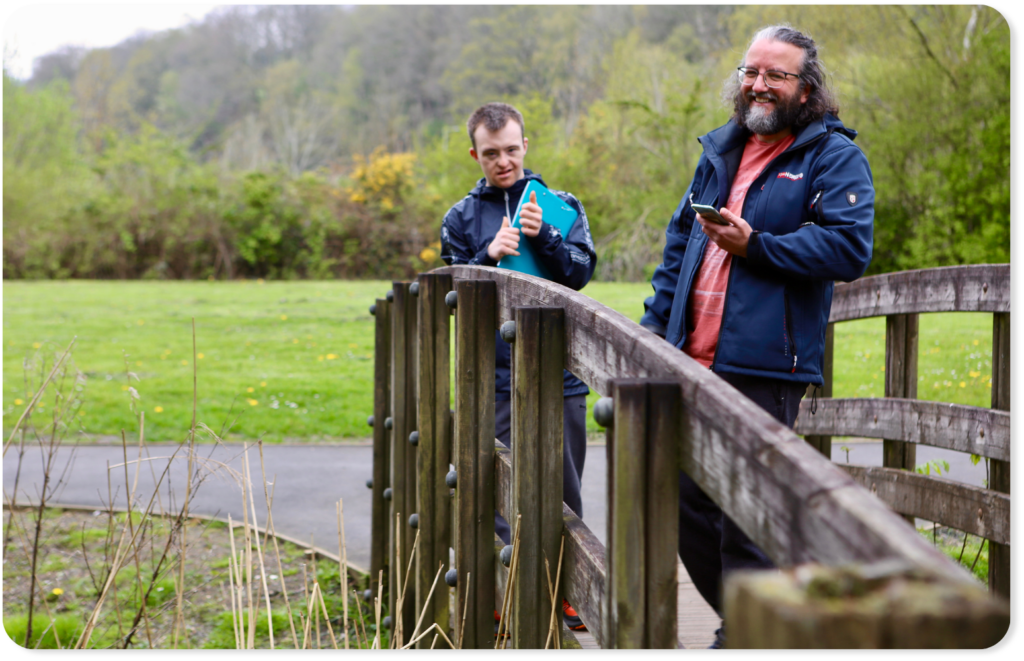 Support worker and person we support standing on a wooden bridge