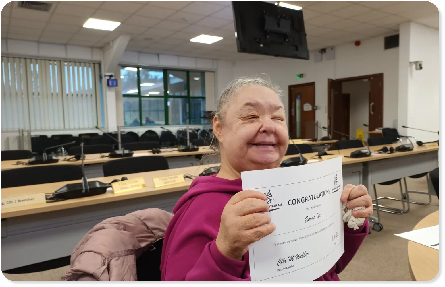 Emma smiling with a certificate from Rhondda Cynon Taf, attending a session about voting with a learning disability