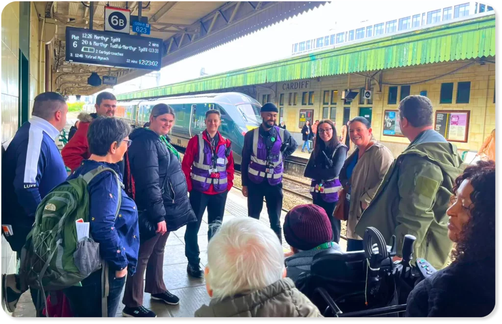 A group of people with disabilities at Cardiff Central train station speaking to Transport For Wales staff