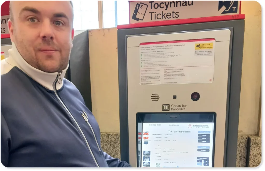 A person with a learning disability using a ticket machine at Cardiff Central train station